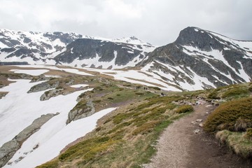 A hiking path amidst snow capped mountains in Ril national park