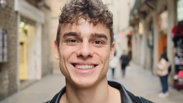 Young handsome man in leather jacket happily smiling on camera outdoor