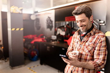 Repairman posing with mobil phone in shop.