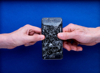 Smartphone écran cassé brisé tenu par deux mains avec réparer