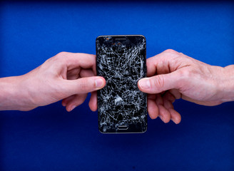 Smartphone écran cassé brisé tenu par deux mains avec réparer