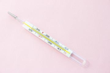 Mercury thermometer on a pink background. Single object