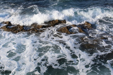 Mediterranean sea waves splashing at the rocks with foam in Chania, Crete Island, Greece.