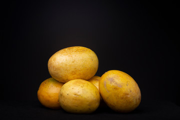 Ripe vibrant yellow Passion fruit fruits against a dark grey background. Studio low key food still life.