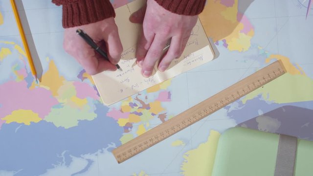 Adventurer writes in a notebook on a table with a map