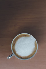 Close-up coffee latte art in cup and milk froth above to drink on wooden table background in the morning.