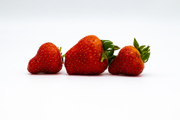 Three whole strawberries with strawberry leaf on on white background