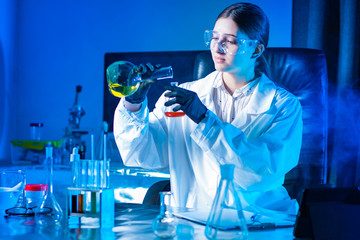 Virologist conducts experiments. Lab technician mixes veins in test tubes. Medic in safety glasses. Epidemiologist at work. Lab technician experimenting with medicines. Attempt to create a vaccine