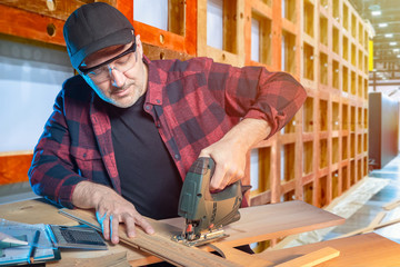 Joiner. A man works in a carpentry workshop. Carpenter working with the jigsaw. Concept - creation...