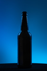 beer bottle with drops drink without label on a blue background