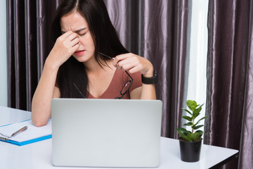 Work from home, Fatigued or strain Asian business young beautiful woman sits on desk workspace feeling tired stressed hold his nose close eyes after see screen long time of laptop computer at office