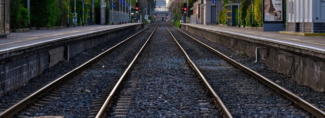 A distance view of empty railway tracks from a train station. Background or banner for delayed or reduced transport concept