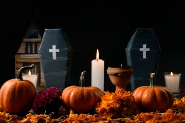 Three pumpkins surrounded with marigold flower, lighted candles and two vertically cardboard...
