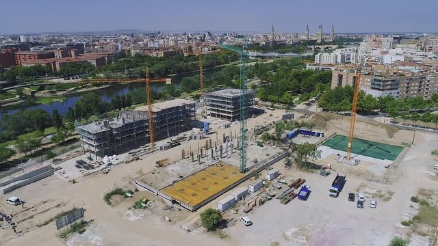 Aerial Drone orbit view of construction site with cranes, trucks, team of workers, Zaragoza, Spain