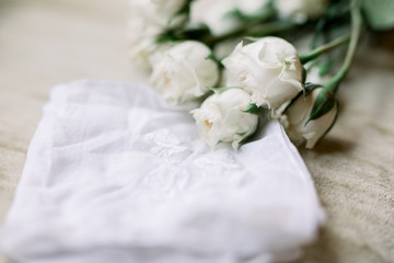 Obraz na płótnie Canvas White Roses Lying Next to a White Embroidered Old-Fashioned Handkerchief, Wedding Photo 