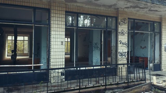 Abandoned building exterior with broken windows. Aerial side view. Low angle shot