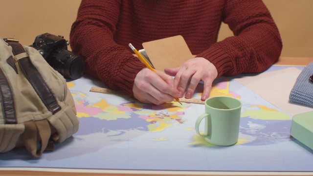 A man draws on a map on a ruler. Close up