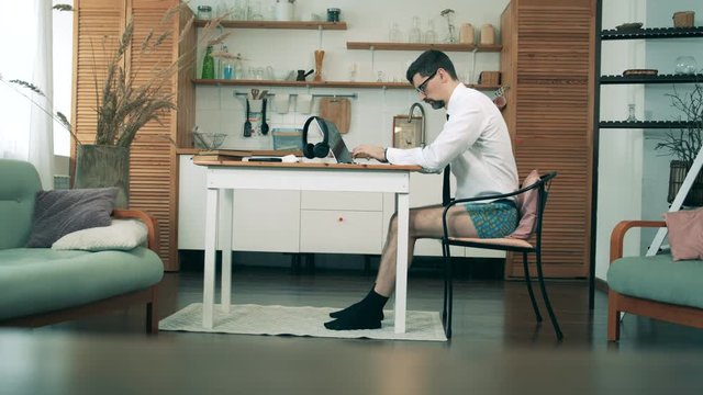 A man with no pants on works with a laptop at home during pandemic.