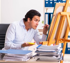 Young handsome employee enjoying painting at the office