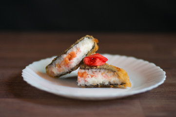 Fried sushi on a white plate with cream cheese, salmon, and ginger. Japanese food. Front photo.