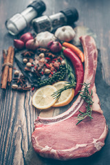 Raw steak sliced cow loin with herbs salt and pepper black stone background close up ingredients for cooking. Top view