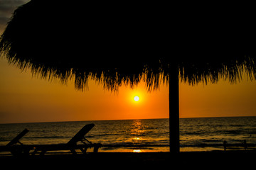 Palapa en la playa durante puesta de sol
