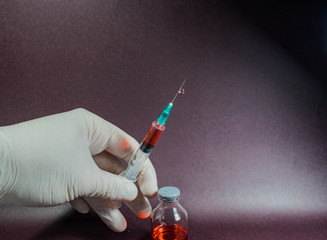 pequeña jeringa y aguja con medicina al lado de pequeñas botellas