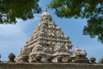 KANCHIPURAM TAMILNADU / INDIA  SEP 11 2011 side view of kailasanathar temple gopuram with blue sky background. view of branches of trees above the gopuram