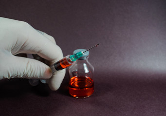 pequeña jeringa y aguja con medicina al lado de pequeñas botellas