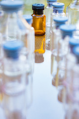 pequeña botella marron con tapa de color gris en medio de botellas trasparentes