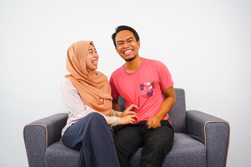 Joyful Muslim husband and wife relaxing at home happy couple together.