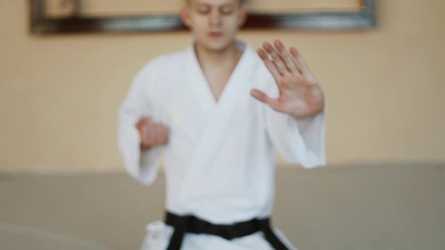 Karate man fighter exercising punching and kicking techniques during training at the dojo.Martial Art Concept