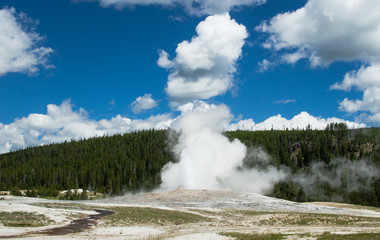 Fountain of old faithful geyser in yellowstone national park meets with clouds in the sky
