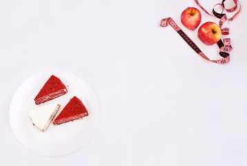 Red apples and pink measuring tape and white plate with cakes on white background.