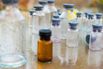 pequeña botella marron con tapa de color gris en medio de botellas trasparentes