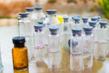 pequeña botella marron con tapa de color gris en medio de botellas trasparentes