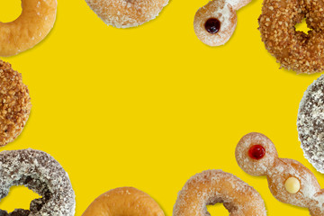 Variety of donuts surrounded around a yellow background, flat lay. Space for text