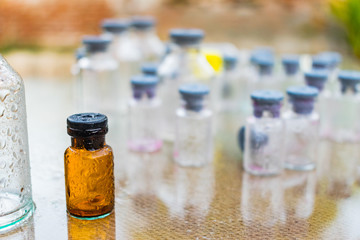 pequeña botella marron con tapa de color gris en medio de botellas trasparentes