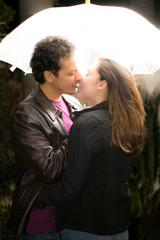 Pareja de novios a punto de darse un beso pajo un paraguas