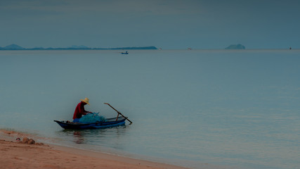 Older man fishing on smal boat in calm seas on the Gulf of Thailand