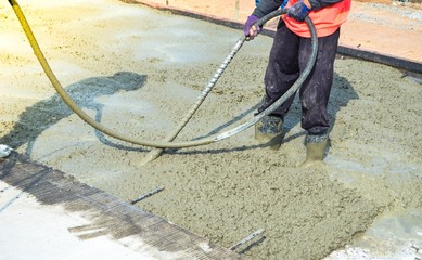 Construction workers using concrete vibrator for concrete density at road pavement construction site. - obrazy, fototapety, plakaty