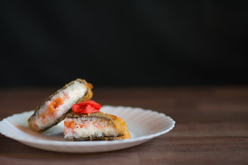 Sushi background. Fried sushi on a white plate with cream cheese, salmon, and ginger. Japanese food. Front photo.