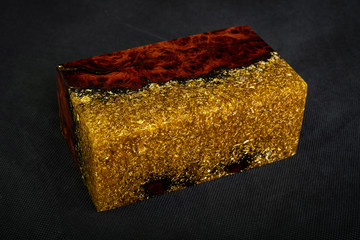 Casting epoxy resin gold with nature burl BURMA PADAUK wood cube on black background
