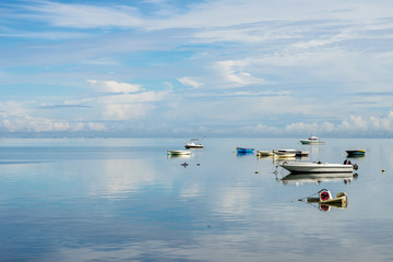 fishing boats against the blue sky, snow-white clouds and transparent ocean water. Mauritius Island, Indian Ocean