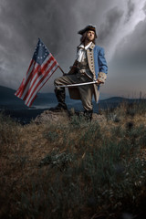 Man in United States War of Independence soldier costume with flag posing in forest. 4th July...