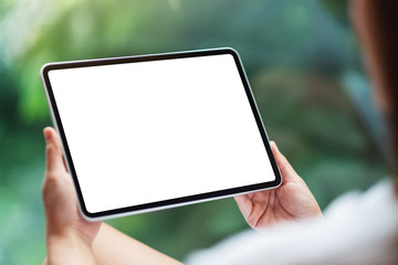 Mockup image of a woman holding black tablet pc with blank white desktop screen , green nature background - obrazy, fototapety, plakaty
