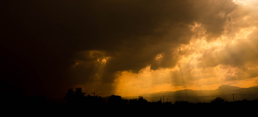 The scene of sunset sky with sunlight penetrates through the clouds. Golden sky background.