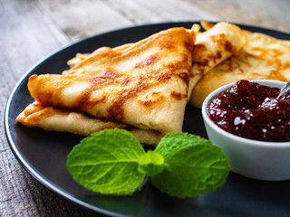Sweet crepes with fruit jam on wooden table
