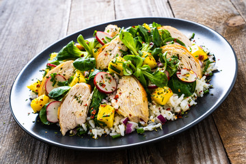 Caesar salad - fried chicken breast, white rice and vegetables on wooden table
