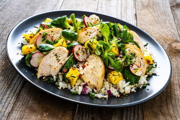 Caesar salad - fried chicken breast, white rice and vegetables on wooden table
